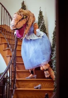 a dinosaur dressed as a princess climbing the stairs in a dress with her mouth open