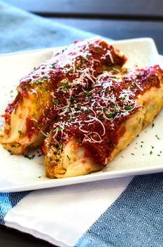 a white plate topped with lasagna covered in sauce and parmesan cheese