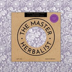 the master herbist logo on a purple and white floral wallpaper with black lettering