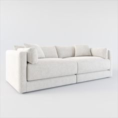 a white couch sitting on top of a white floor next to a wall with pillows