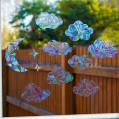 an image of some stars and moon in the sky through a glass window with wood fence behind it