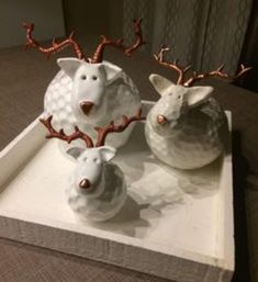 three white ceramic animals sitting on top of a tray with antlers in the shape of deer heads