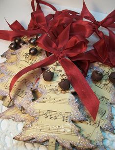 an ornament made out of sheet music with red ribbon and bells on it