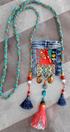 a colorful beaded necklace with tassels and beads hanging from it's side