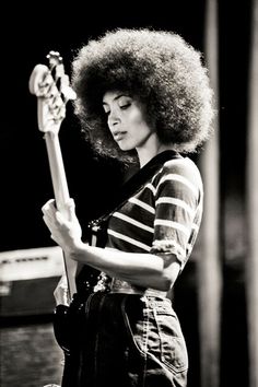 a woman with an afro holding a guitar