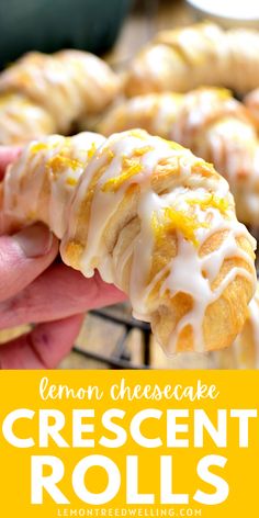 lemon cheesecake crescent rolls with icing being held up by a hand over a tray of other pastries