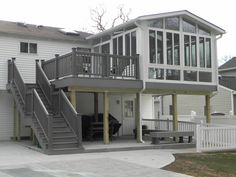 a two story house with stairs leading up to the second floor and an attached deck