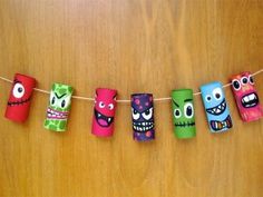 some paper rolls are hanging on a string with eyes and mouths painted on them in different colors