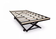 a metal bed frame sitting on top of a white floor next to a wooden table