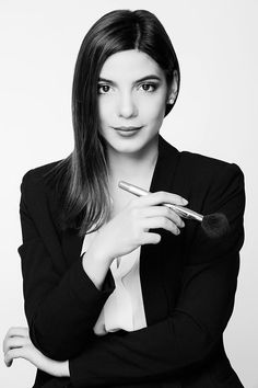 black and white photograph of a woman holding a brush in her right hand while looking at the camera