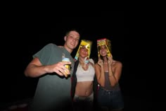 two women and a man are posing for the camera with food on their heads in front of them