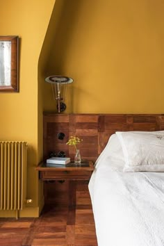 a bedroom with yellow walls and white bedding