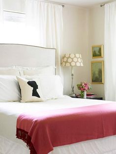 a bed with white sheets and pink blankets