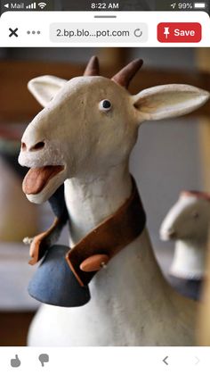 a ceramic goat with a leather collar around its neck and tongue hanging from it's back