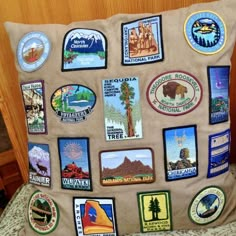 a pillow with many different stickers on it sitting on a bed next to a wooden headboard