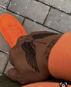 a person's arm with tattoos on it and an orange shoe