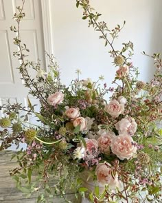 a vase filled with lots of pink flowers on top of a table next to a door