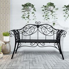 a black metal bench sitting next to potted plants