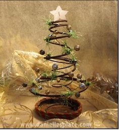 a small christmas tree made out of wire and glass beads is displayed on a table