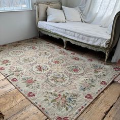 a white day bed sitting next to a window in a room with wooden floors and walls