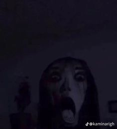 a woman with her mouth open in the dark, making a creepy face at night