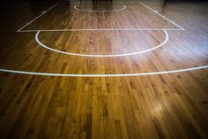 an empty basketball court with white lines on the wood floor in a gym or gymnasium