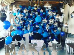 blue and silver balloons are hanging from the ceiling