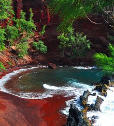 the red sand beach is surrounded by green trees