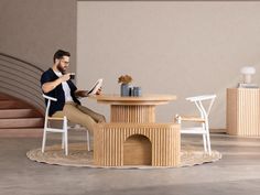 a man sitting at a table reading a book in front of a dog house shaped coffee table