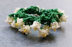 a close up of a bracelet made out of green and white beads on a gray surface