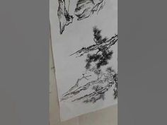 an ink painting on paper with trees and mountains in the background, hanging on a wall