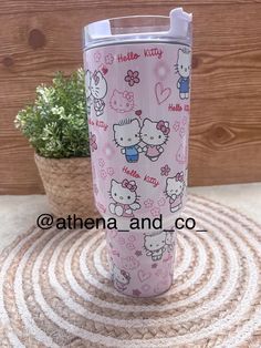 the hello kitty tumbler cup is next to a potted plant on a rug