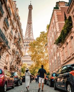 two people walking down the street in front of the eiffel tower