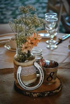 a vase with flowers in it sitting on top of a wooden table next to glasses