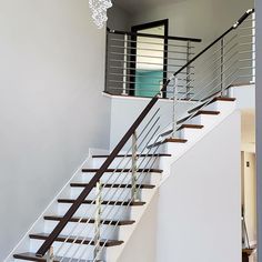 a white staircase with metal railing and chandelier