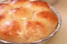 a pan filled with bread sitting on top of a counter next to a bowl full of rolls