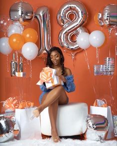 a woman is sitting on a couch with balloons and presents