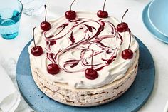 a cake with white frosting and cherries sitting on top of a blue plate