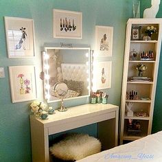 a white vanity with lights on it in a bedroom next to a bed and bookcase