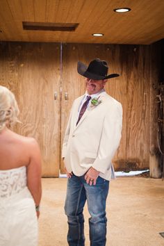 a man wearing a cowboy hat standing next to a woman in a white dress shirt and jeans