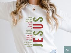 a woman wearing a white sweatshirt with the words jesus printed on it in green and red