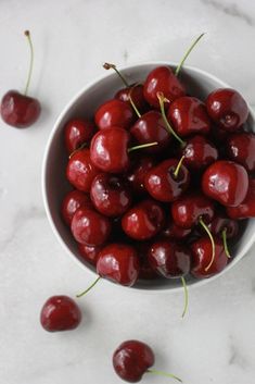 a white bowl filled with cherries on top of a table