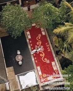 an aerial view of a red carpet on the ground in front of some trees and bushes