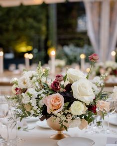 a vase filled with lots of flowers on top of a white table cloth covered table