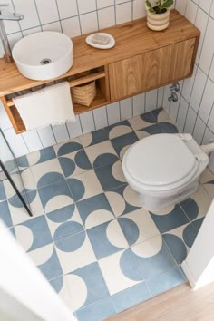 a white toilet sitting in a bathroom next to a wooden counter top with a sink