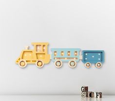 three wooden toy trains are lined up against a white wall with the word stop spelled out