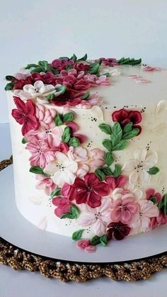 a white cake with pink and red flowers on it