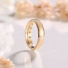 a gold wedding ring with stars on the inside, sitting on top of a table