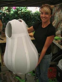 a woman standing next to a large white vase