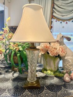 a lamp sitting on top of a table next to flowers